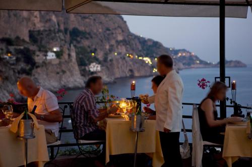 a group of people sitting at tables in a restaurant at Villa Corallium in Praiano