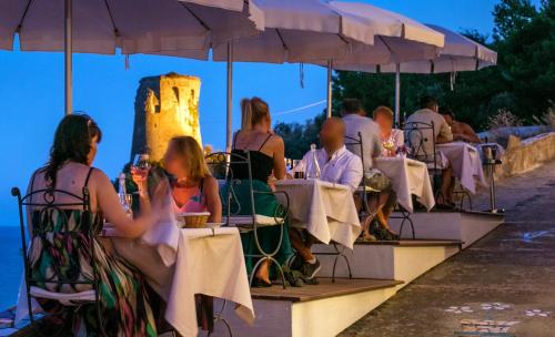 a group of people sitting at tables under umbrellas at Villa Corallium in Praiano