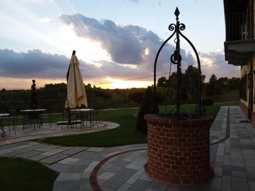 a patio with an umbrella and tables and a sunset at B&B Cascina Bellavista in Tigliole