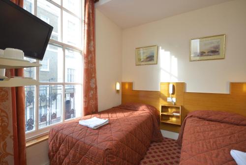 a hotel room with two beds and a window at Seymour Hotel in London