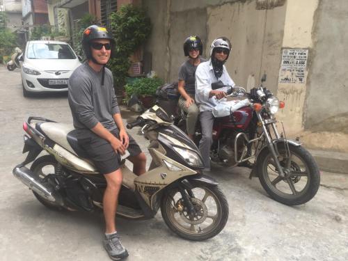 three men are sitting on motorcycles on the street at Hue Lovely Homestay in Hue