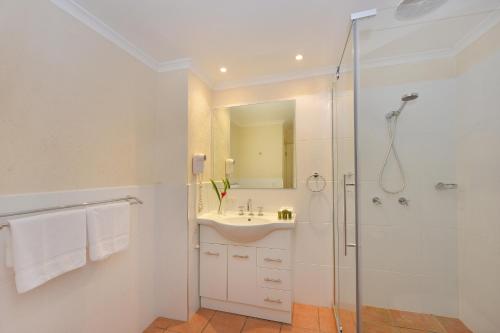 een witte badkamer met een wastafel en een douche bij Seascape Holidays - Tropic Sands in Port Douglas