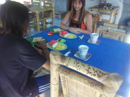 due persone sedute a un tavolo blu con del cibo di Dinoyin Bungalows a Gili Meno