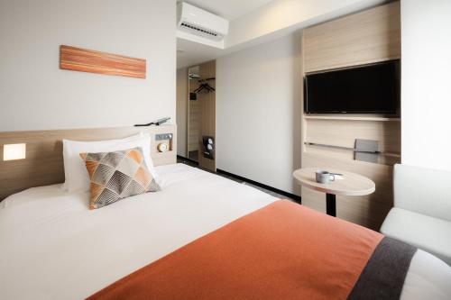 a hotel room with a bed and a television at Tissage Hotel Naha by Nest in Naha