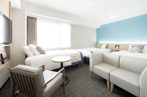 a hotel room with two beds and a couch at Tissage Hotel Naha by Nest in Naha