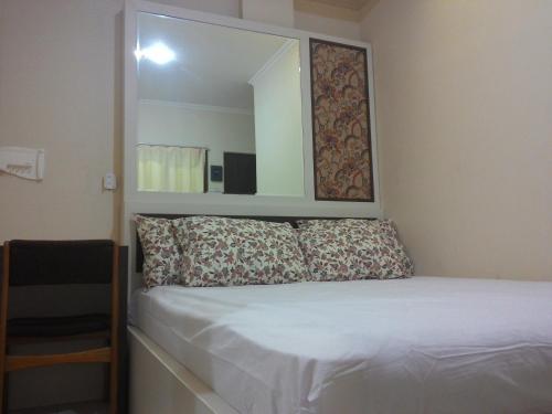 una camera da letto con un letto con uno specchio sopra di esso di Kantos Guest House a Giacarta