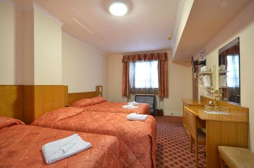 a hotel room with two beds and a desk at Seymour Hotel in London