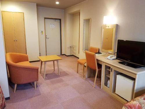 a room with a desk with chairs and a television at Hakuba Hotel Hana-no-Sato in Hakuba
