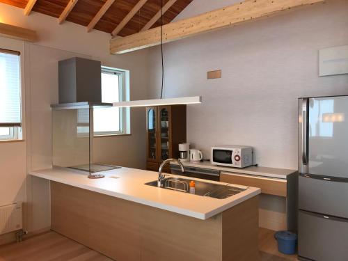 a kitchen with a sink and a refrigerator at Tsuru Apartments in Furano