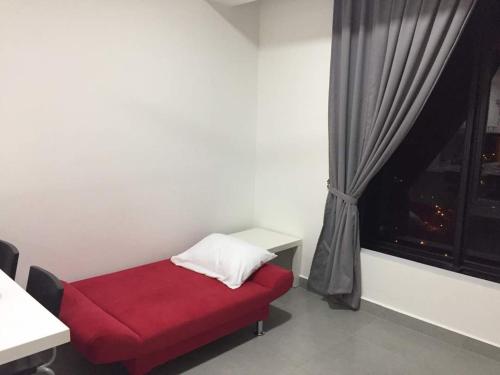a red bed in a room with a window at Mayzi Holiday Home @ Cyberjaya in Cyberjaya