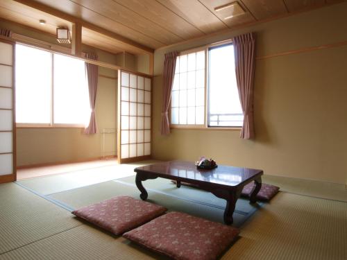 a living room with a table and two windows at Hakuba Hotel Hana-no-Sato in Hakuba