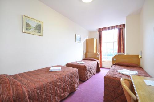 a hotel room with two beds and a table at Seymour Hotel in London