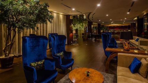 a lobby with blue chairs and a table at The Arista Hotel Palembang in Palembang