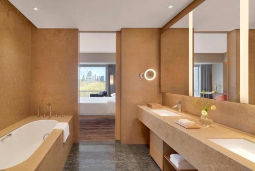 Hyatt Regency Beijing Wangjing في بكين: حمام به مغسلتين ومرآة كبيرة