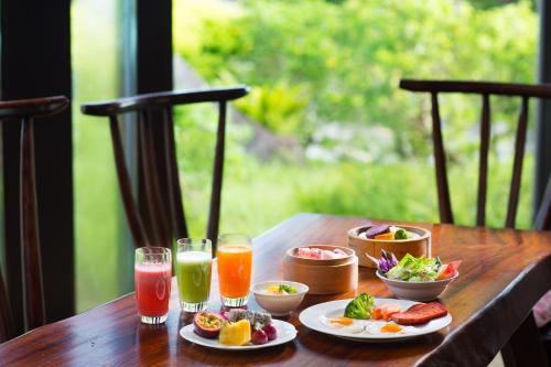 una mesa de madera con platos de comida y bebidas en Coco Garden Resort Okinawa, en Uruma