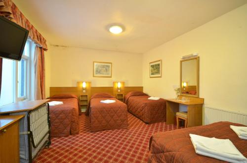 a hotel room with three beds and a television at Seymour Hotel in London