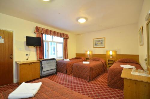 a hotel room with three beds and a television at Seymour Hotel in London