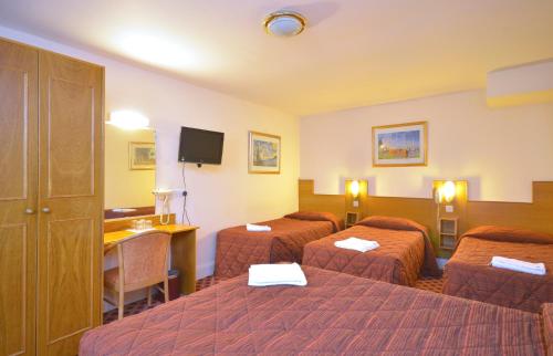 a hotel room with three beds and a desk at Seymour Hotel in London