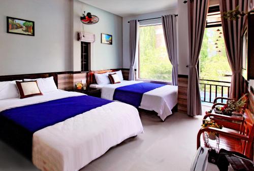 um quarto de hotel com duas camas e uma varanda em An Thinh Homestay em Hoi An