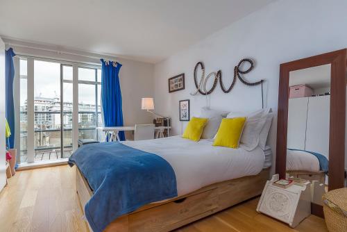 a bedroom with a bed with a love sign on the wall at Spectacular River Thames View in London