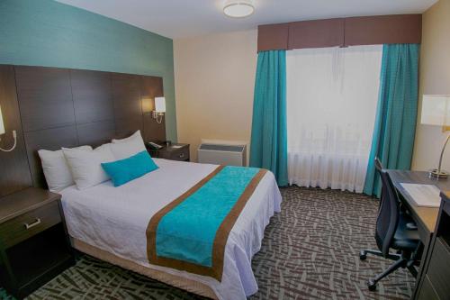 a hotel room with a bed and a desk and a window at Best Western Plus Barrie in Barrie