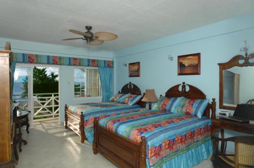 sypialnia z 2 łóżkami i wentylatorem sufitowym w obiekcie Kalinago Beach Resort w mieście Saint Georgeʼs