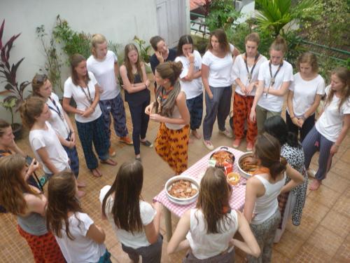 a group of women standing around a table with pizza at Jojies Homestay Fortkochi in Cochin