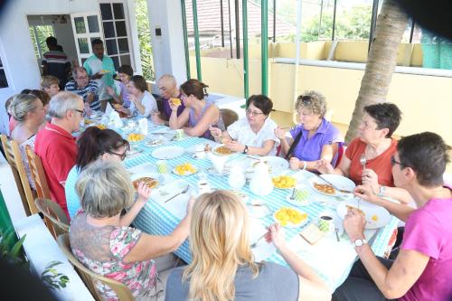 a group of people sitting at a table eating food at Jojies Homestay Fortkochi in Cochin