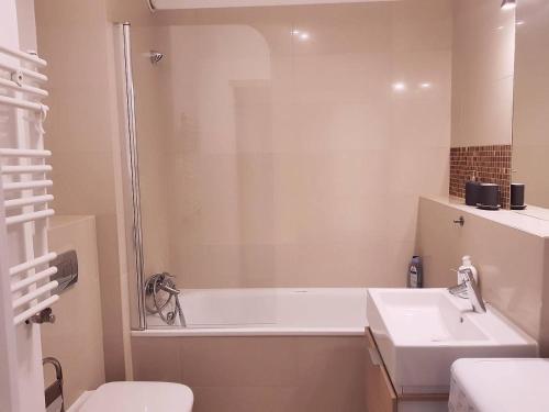 a bathroom with a tub and a sink and a toilet at Family Apartment Golden Tulip in Międzyzdroje