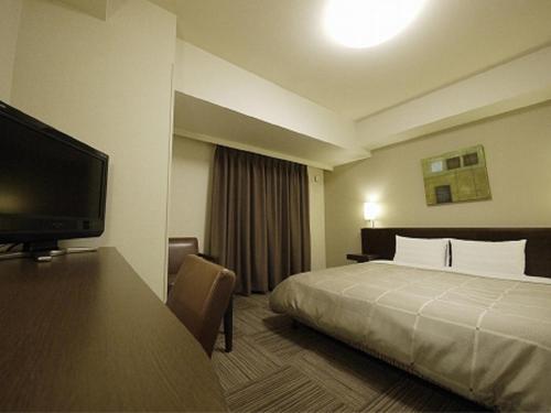 a hotel room with a bed and a flat screen tv at Hotel Route-Inn Iwaki Ekimae in Iwaki