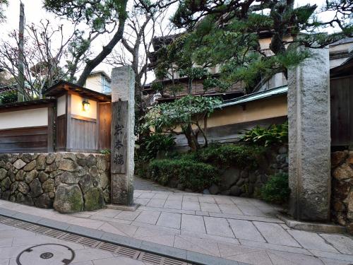 a building with a stone wall next to a sidewalk at Iwamotoro in Fujisawa
