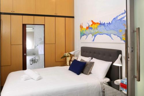 a bedroom with a large white bed and a bathroom at Saint George - The Townhouse in Melbourne