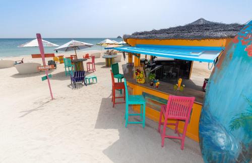 a bar on the beach with colorful chairs and umbrellas at Radisson Blu Resort, Fujairah in Dibba