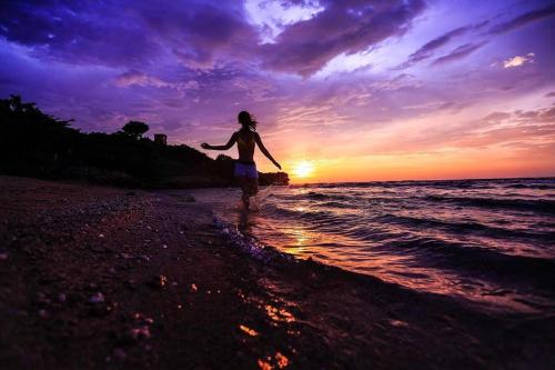 a woman walking on the beach at sunset at Venice Seaview Hotel in Xiaoliuqiu