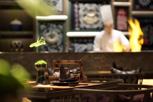 a restaurant with a table with a waiter in the background at Wanda Realm Liuzhou in Liuzhou
