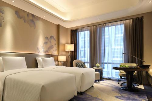 a hotel room with two beds and a desk at Wanda Realm Liuzhou in Liuzhou