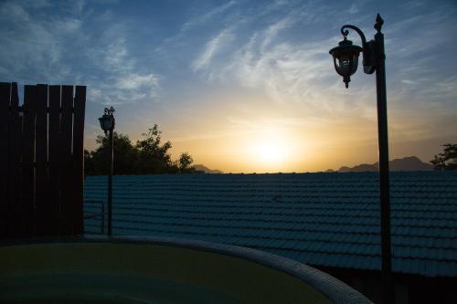 two street lights and a field at sunset at The Colonial Manek Manor By SAH in Mount Ābu