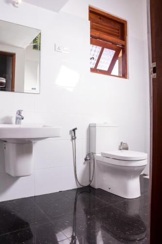 a white bathroom with a sink and a toilet at Channa Villa & Tours in Bentota
