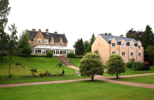 una grande casa su una collina con alberi di fronte di Inverness Lochardil House a Inverness