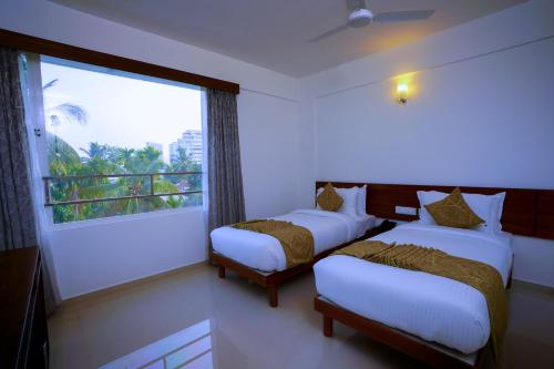 two beds in a room with a large window at Niko Hotels in Cochin