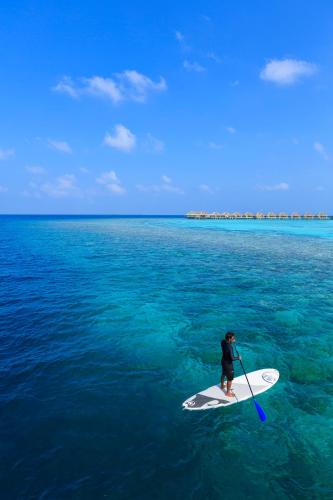 a person on a paddle board in the water at Dusit Thani Maldives - 50 percent discount on transfers for stays until 20 Dec 2025 in Baa Atoll