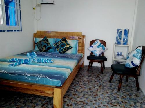 a bedroom with a bed with blue sheets and two chairs at Bolo Beach Santorini nearby to Hundred Island in Alaminos