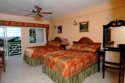 a hotel room with two beds and a balcony at Kalinago Beach Resort in Saint Georgeʼs
