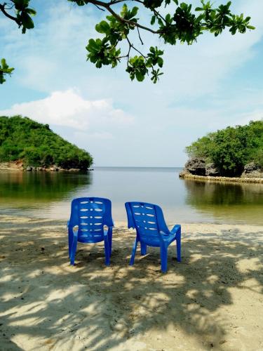 two blue chairs sitting on a beach near the water at Bolo Beach Santorini nearby to Hundred Island in Alaminos