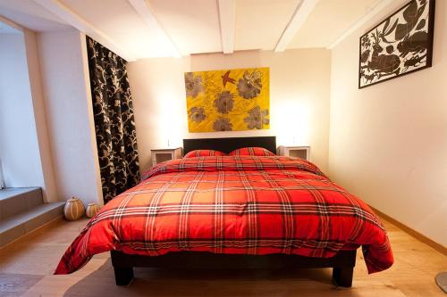 a bedroom with a bed with a red blanket at Les Arts Verts in Kruth