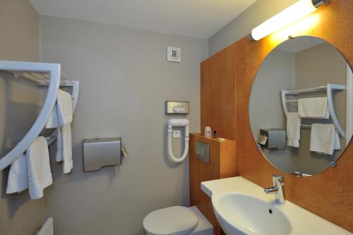 a bathroom with a sink and a mirror and a toilet at Hôtel du Parc Nantes Ouest Orvault in Orvault