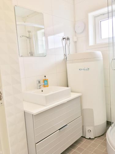 a white bathroom with a sink and a refrigerator at Cape Marina Penthouse in Skarsvåg