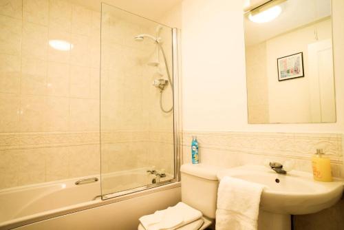 ALTIDO Elegant 2 bed, 2 bath flat, patio and free parking في إدنبرة: حمام مع حوض ودش وحوض استحمام