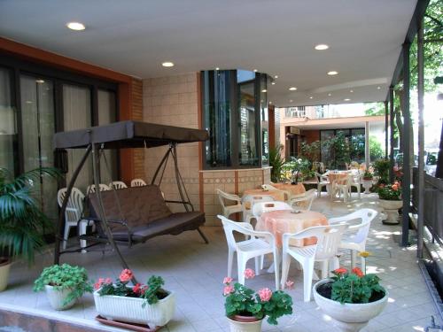 d'une terrasse avec des tables, des chaises et un parasol. dans l'établissement Hotel Eureka, à Rimini