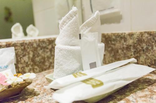 een stapel handdoeken op een aanrecht in een badkamer bij 24@Home Hotel in Nonthaburi